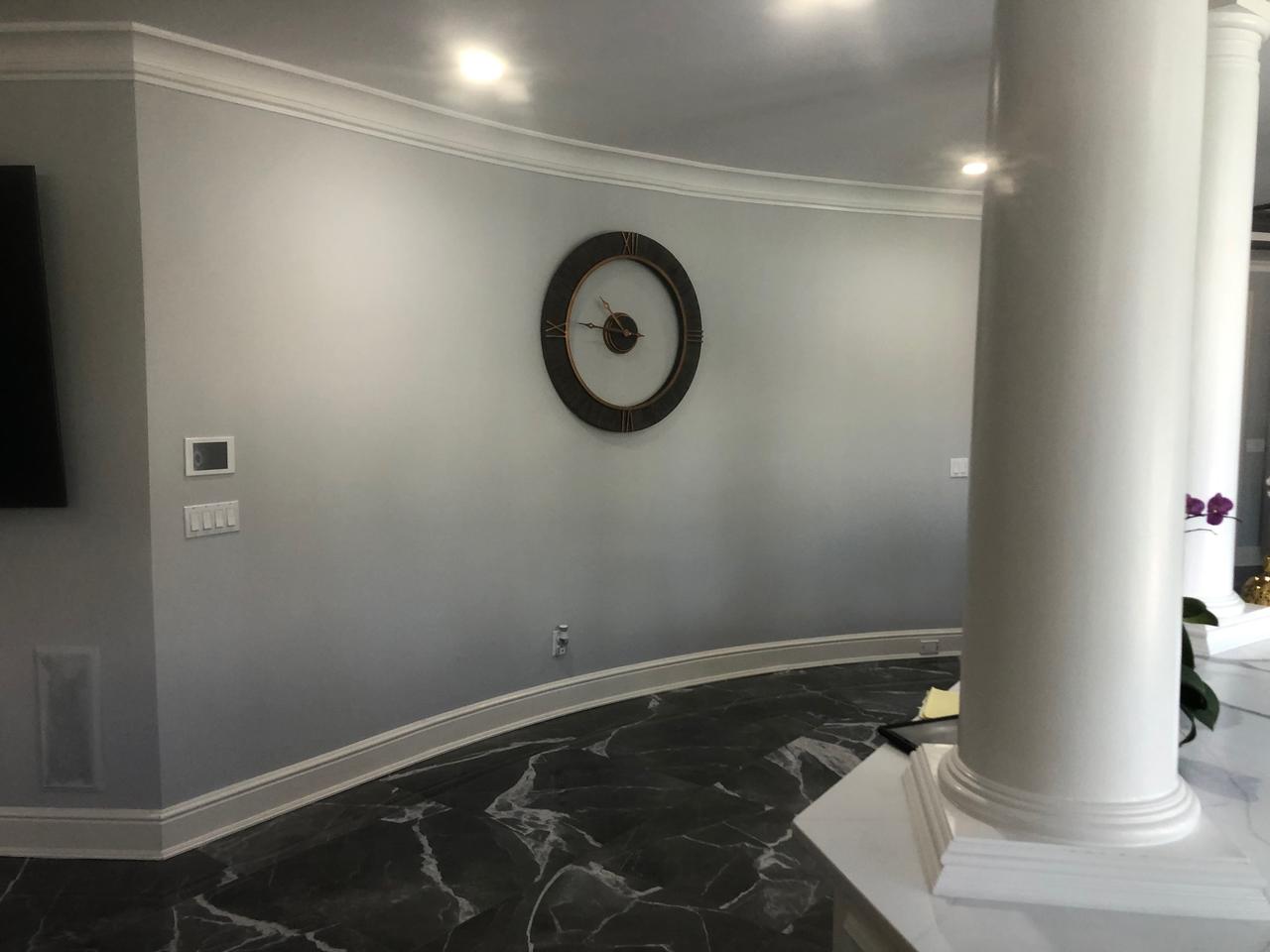 Curved hallway wall with clock and marble floor